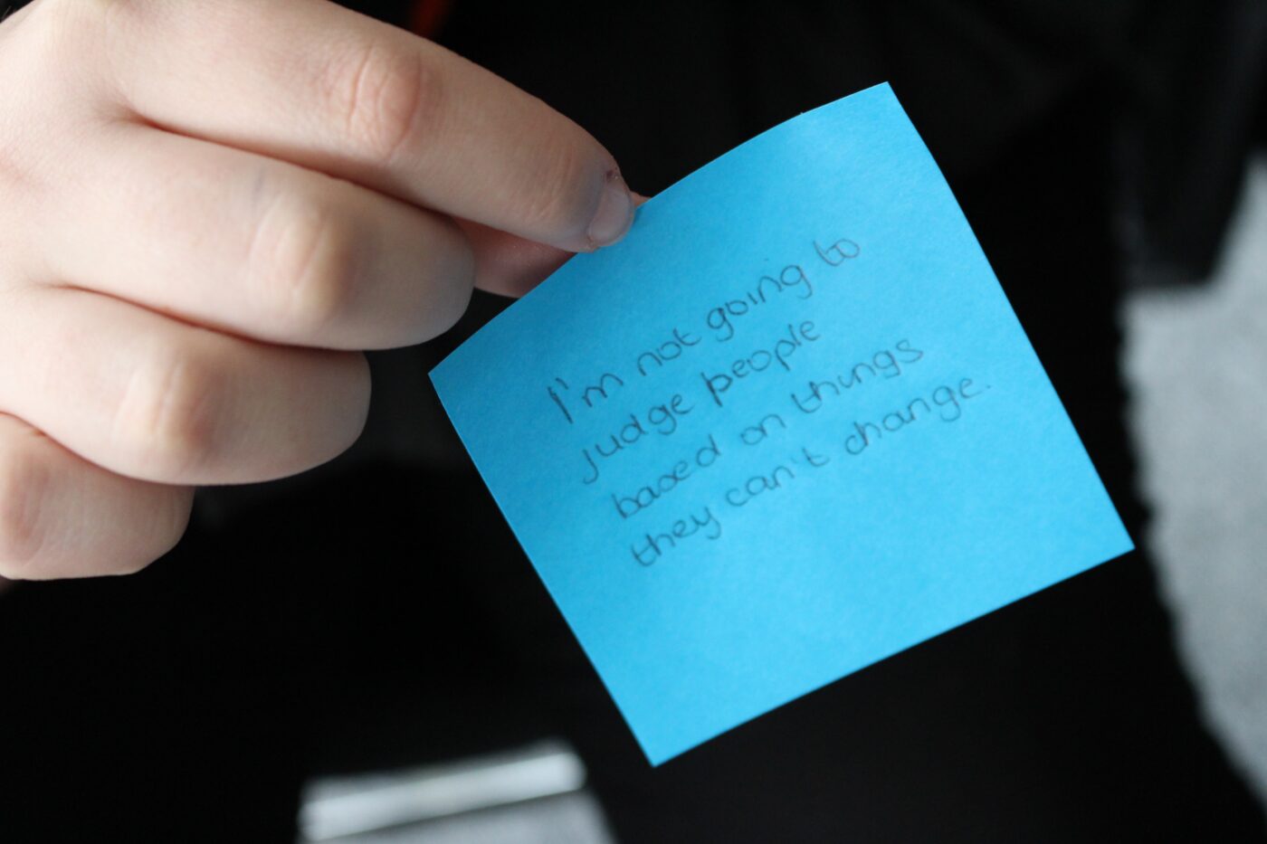 Written on a post-it note are the words I'm not going to judge people based on things they can't change.