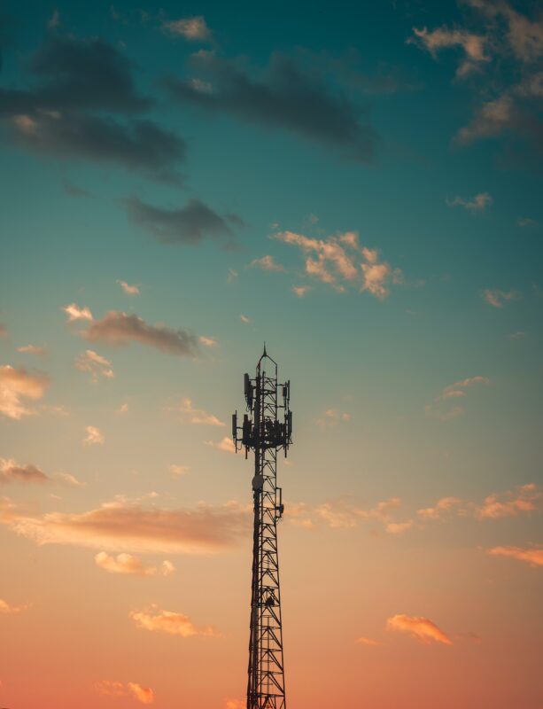A communications tower is silhouetted against a blue and orange sunset sky.