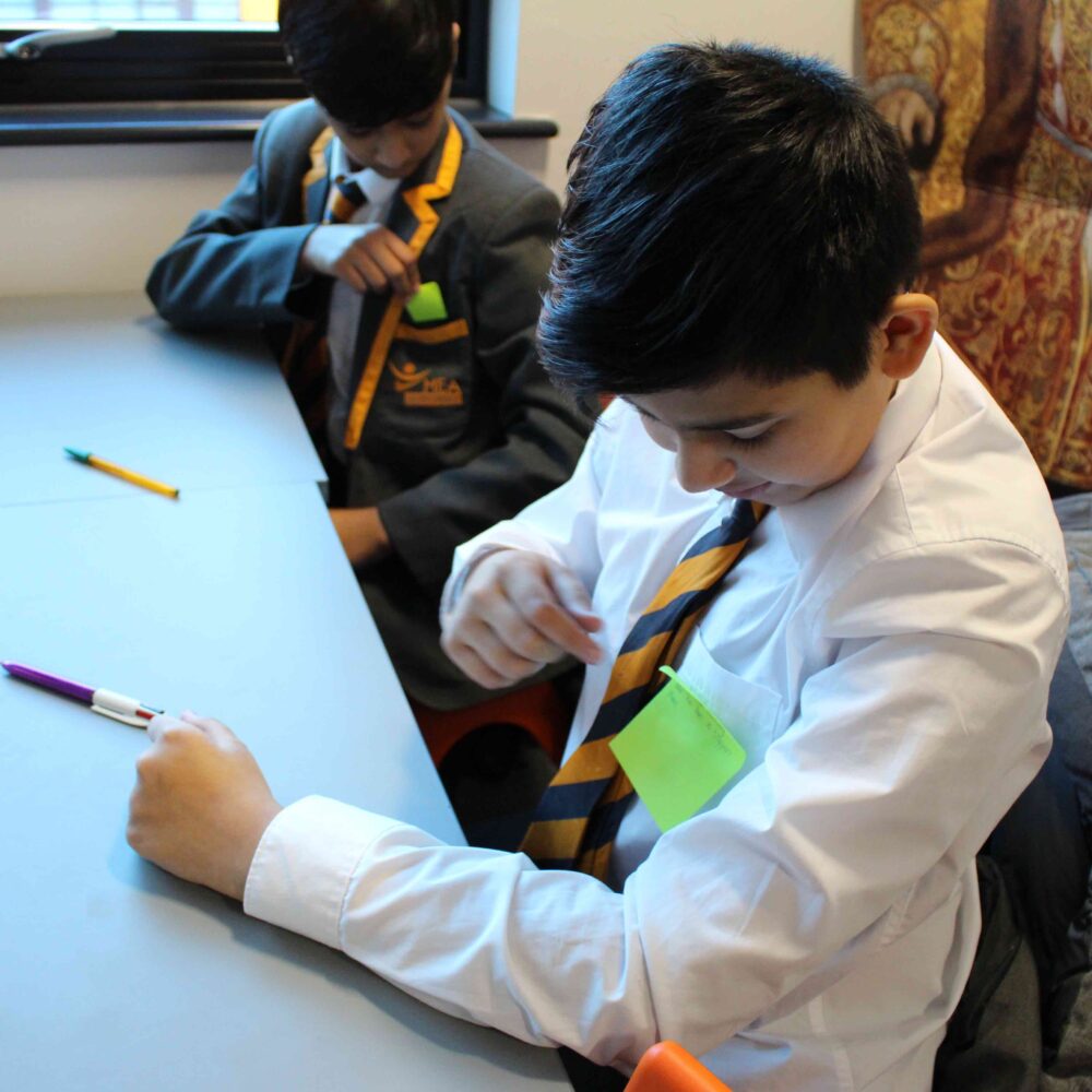 A student sticking his equalities pledge sticky note to his school uniform