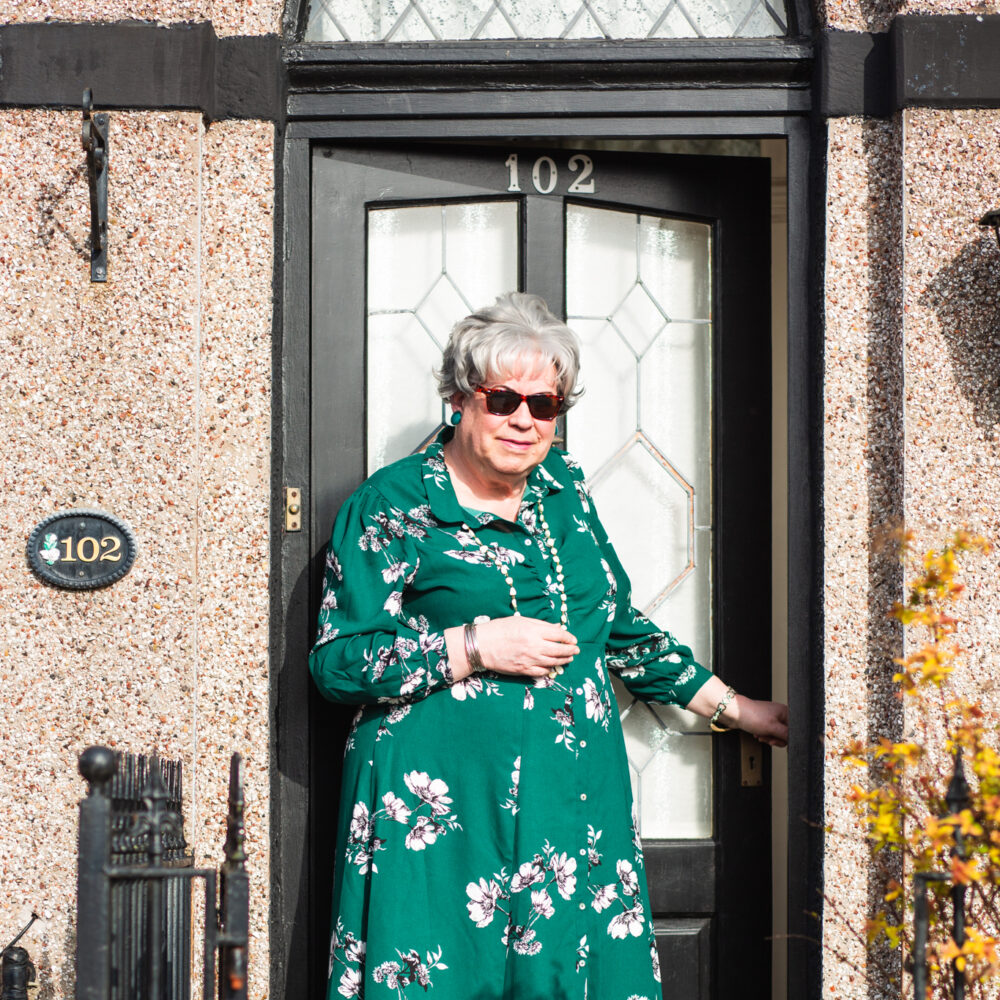 Photo of participant Pauline, standing outside her house and wearing sunglasses