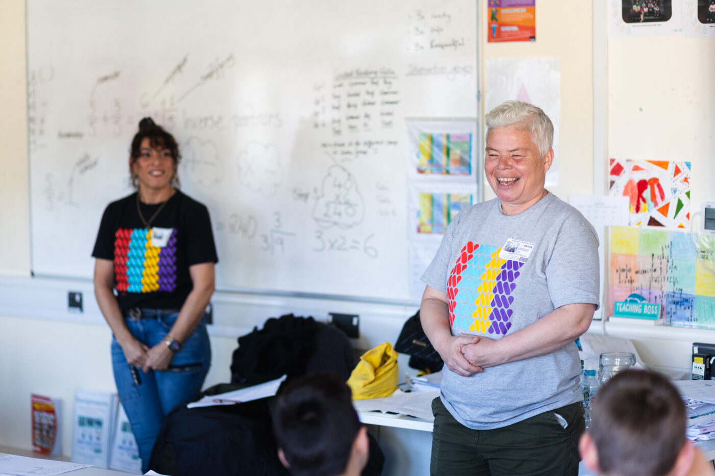 An artist and facilitator laughing at the front of a classroom