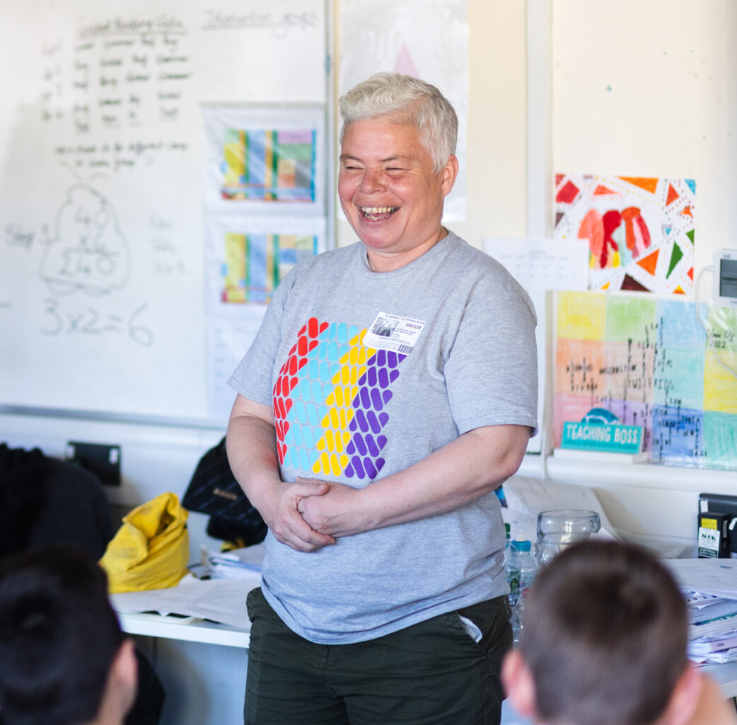 An artist and facilitator laughing at the front of a classroom