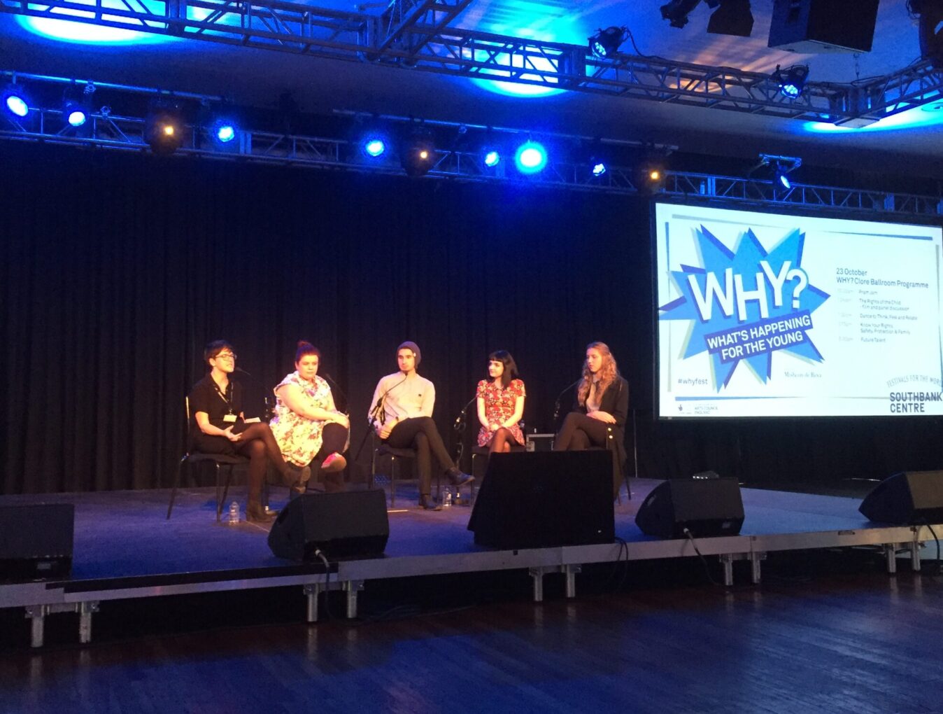 A group of adults sat on chairs at WHY festival speaking as part of a panel