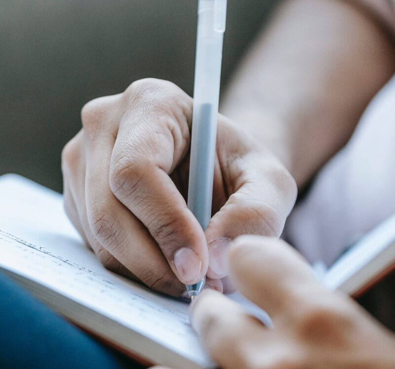 A hand writing in a notebook