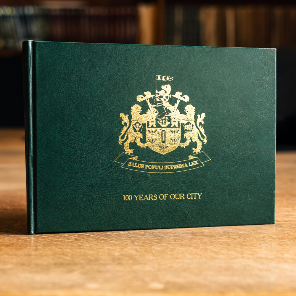 A green hardback book with the words 100 years of our city stands on a table in Salford Museum's local history library.
