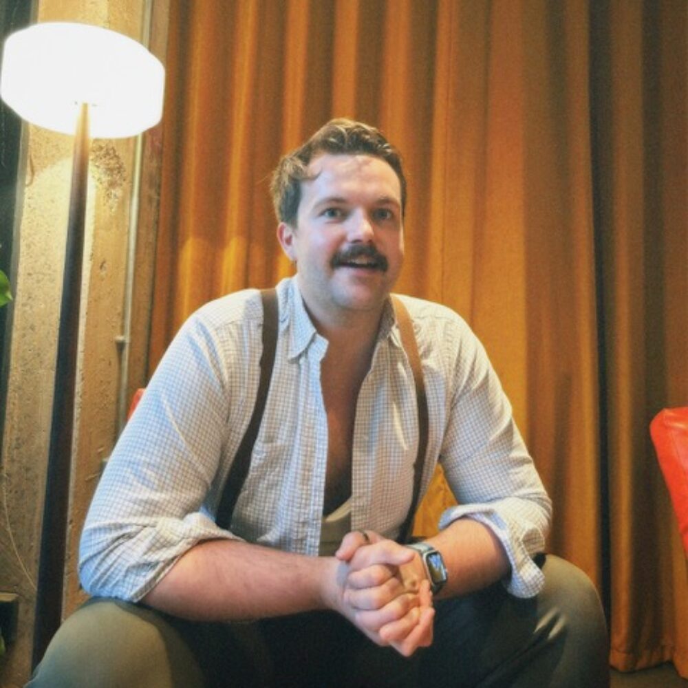 A photo of Louis Glazzard, a man in a white shirt and brown braces.