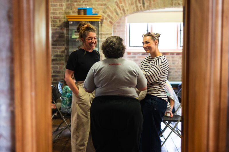 Three people stood chatting and laughing.