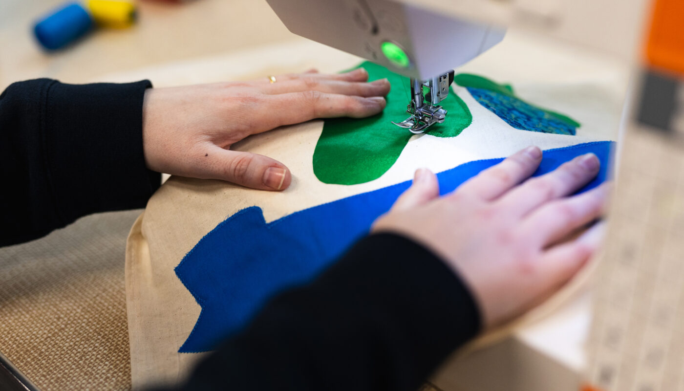A participant using a sewing machine to stitch a banner