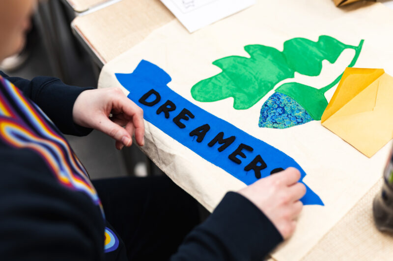 A participant places letters on a small banner that spells DREAMERS