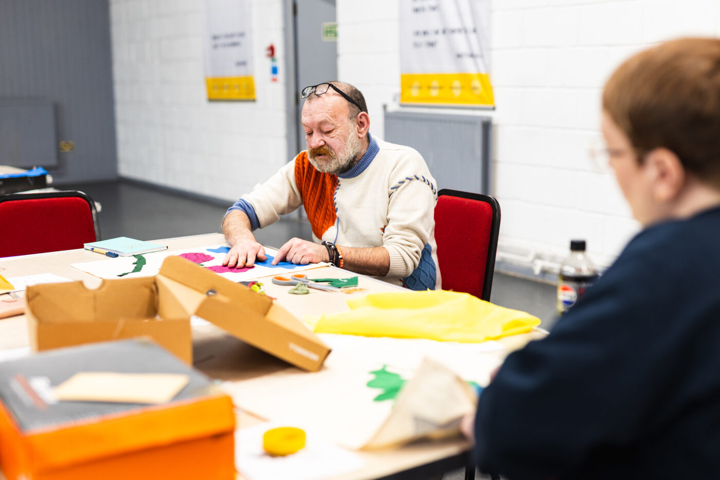A community collaborator hand sews a banner