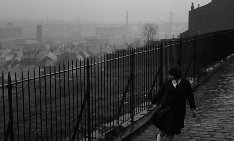 A black and white still from the 1961 film A Taste of Honey of a woman walking in Salford.
