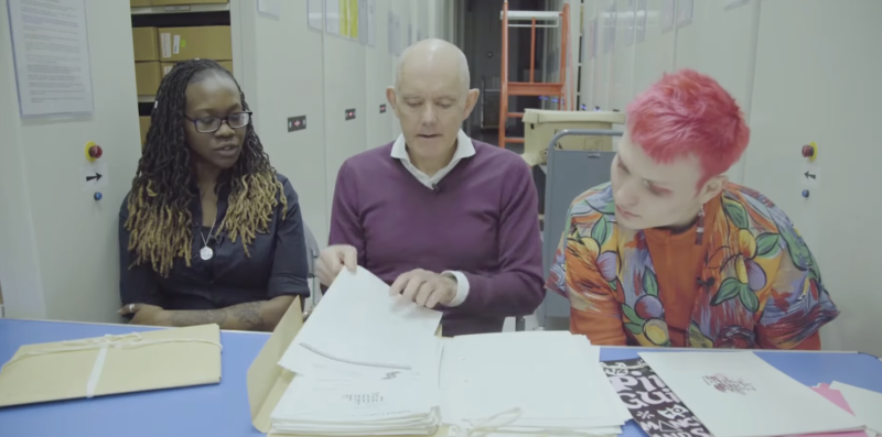 A still from The Pink Guide short documentary by the University of Salford's Student Union with three people sat reading the guide.