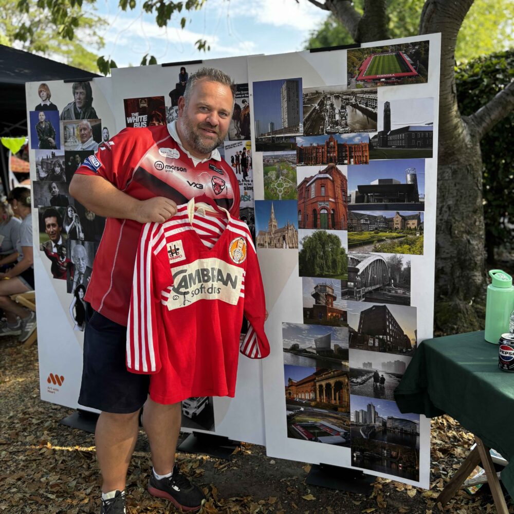 Matt Smith smiles holding a Salford Red Devils retro jersey