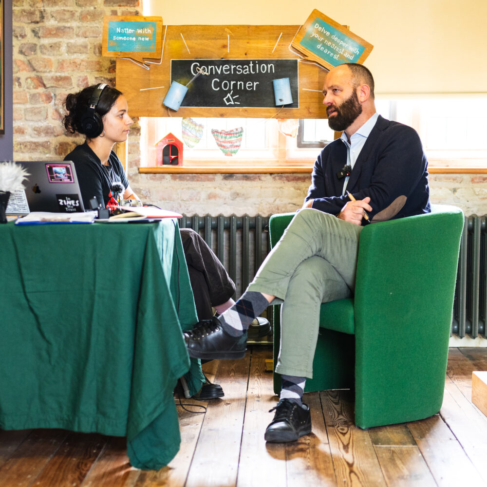 A photo of Mayor of Salford Paul Dennett talking to a person with headphones on.
