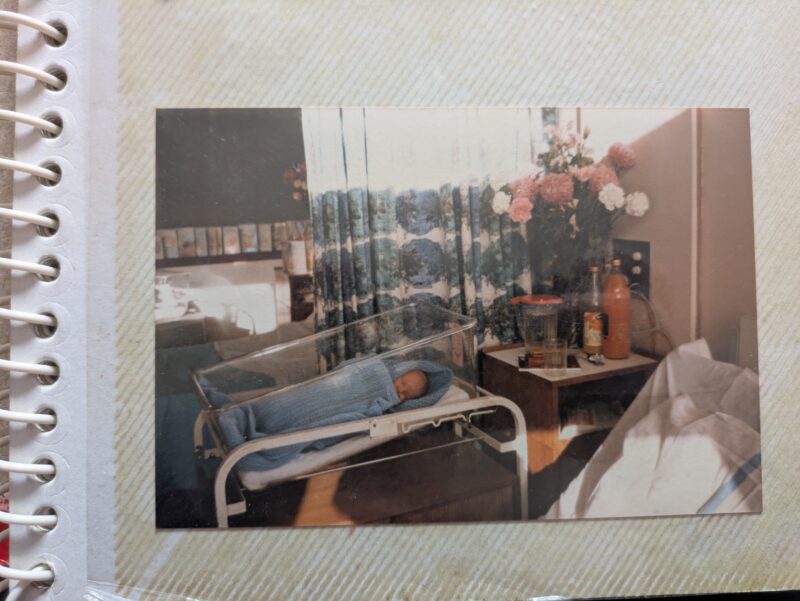 An image of a newborn baby wrapped in a blue blanket in a hospital.